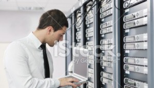 stock photo 15505031 businessman with laptop in network server room e1402332269928